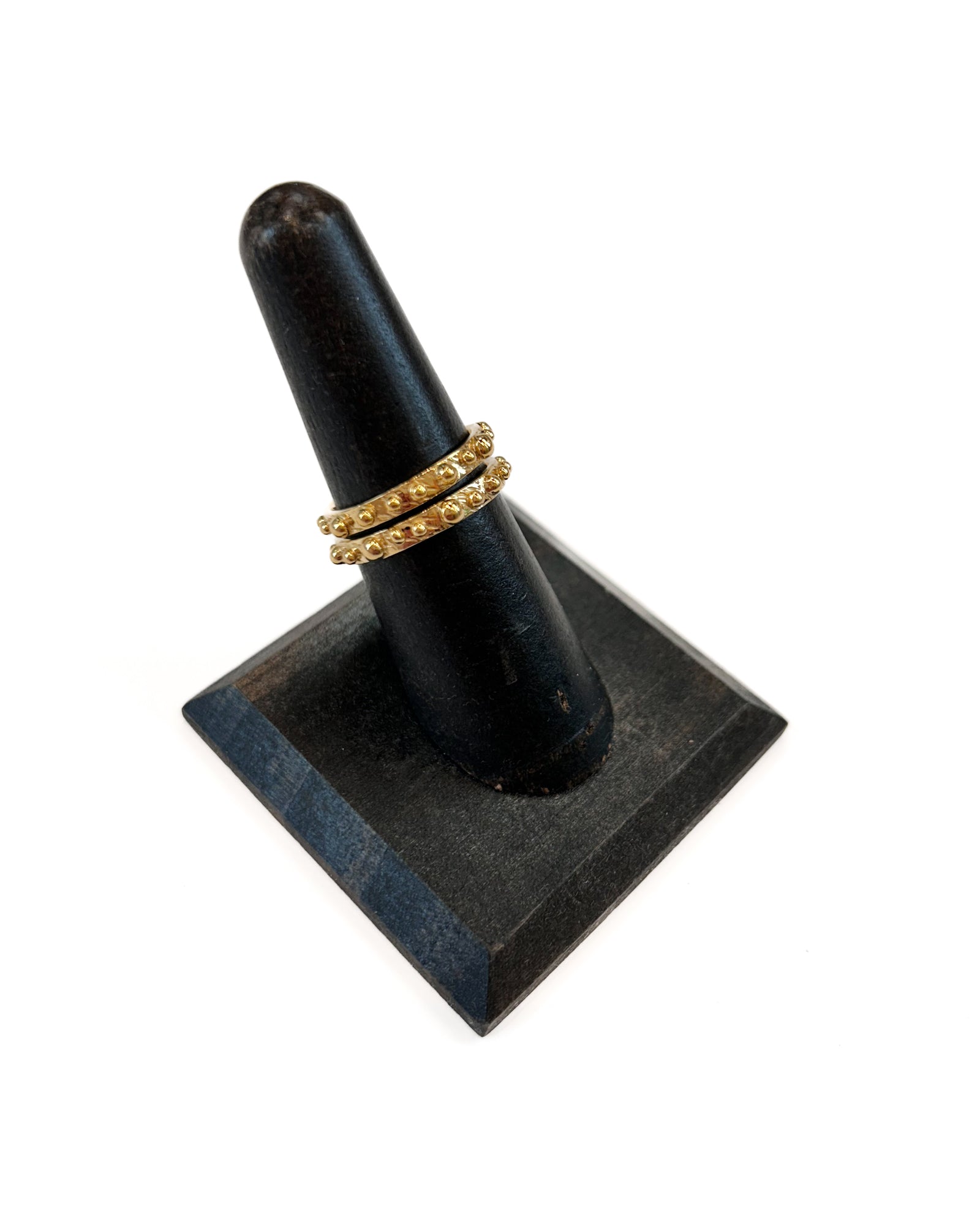 Two gold rings with beaded designs on a white background