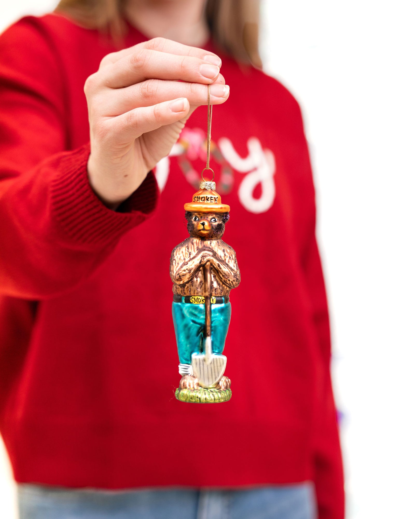 Person holding a Smokey Bear ornament with a white background