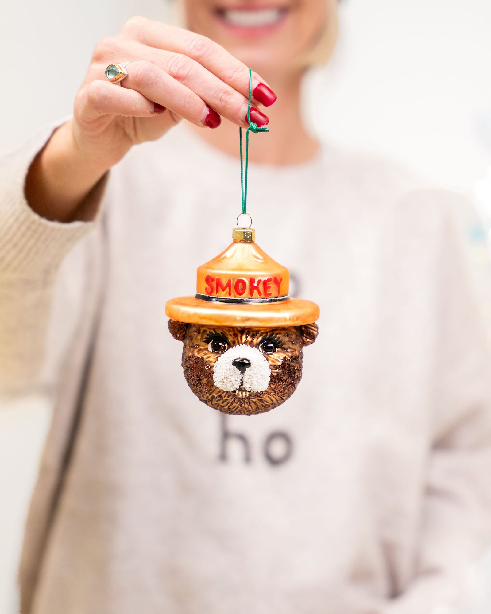 Person holding a Smokey Bear ornament with a white background