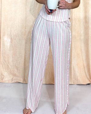 Person wearing pink and white striped pajama pants against a beige curtain background