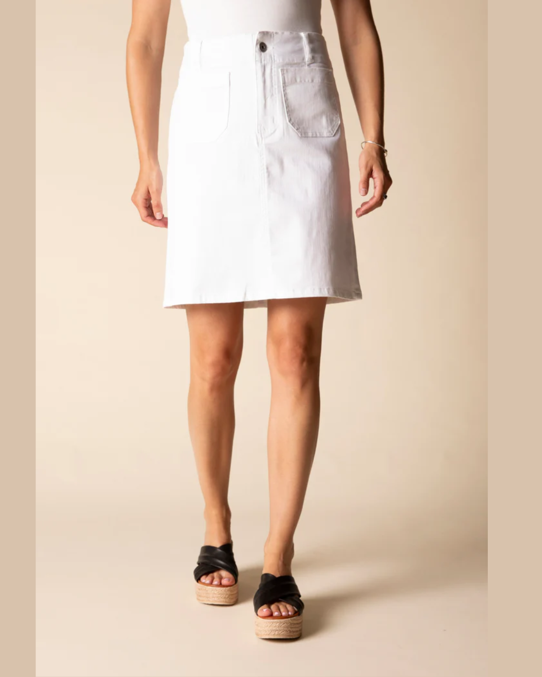 Person wearing a white denim skirt on a beige background