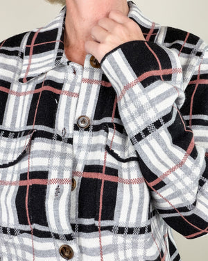 Close-up of a person wearing a black, white, and gray plaid button-up shirt with thin red stripes, showing the collar, front buttons, and a hand adjusting the collar.