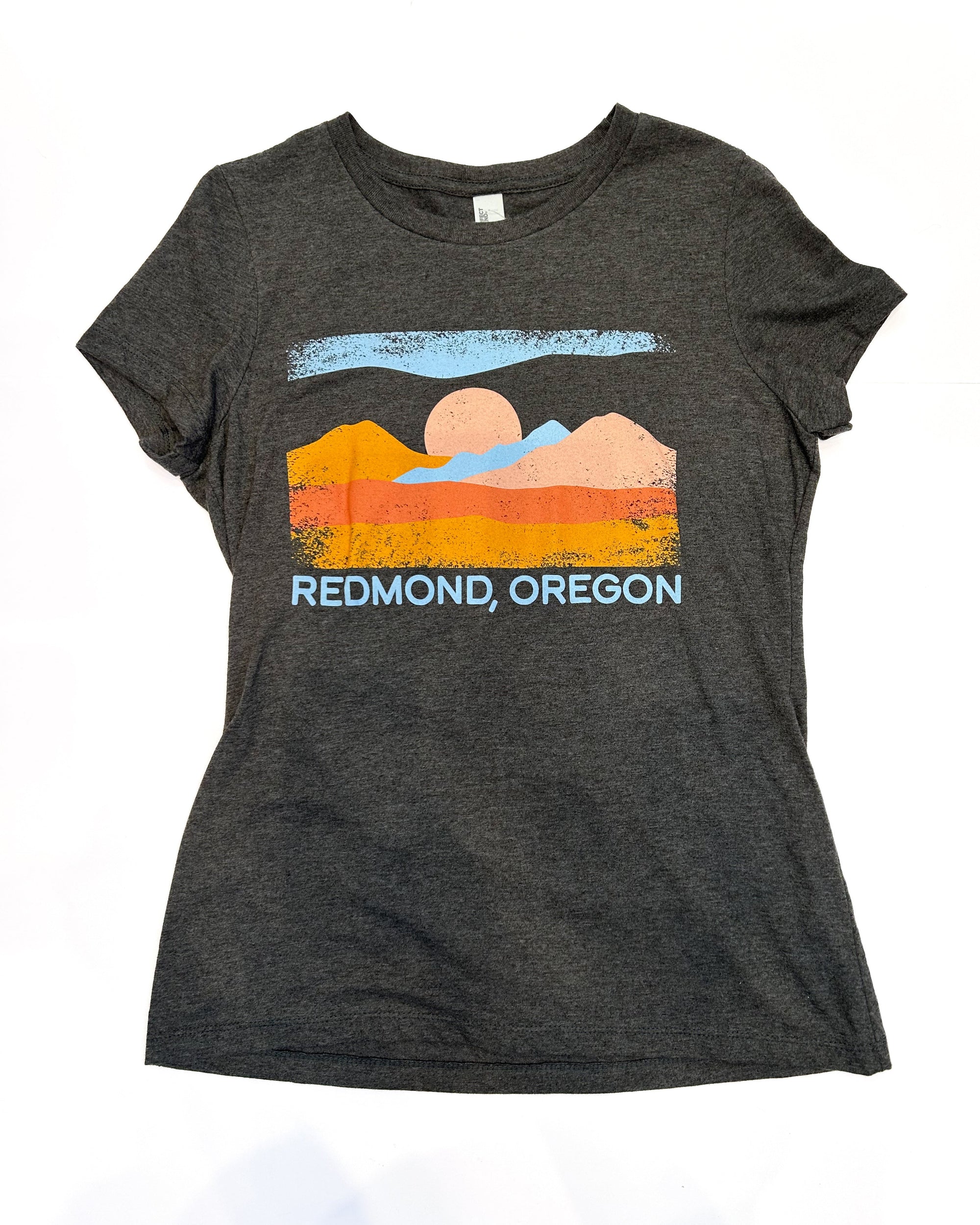 Gray t-shirt with a scenic design and 'Redmond, Oregon' text, paired with blue jeans on a white background.