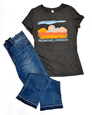 Gray t-shirt with a scenic design and 'Redmond, Oregon' text, paired with blue jeans on a white background.