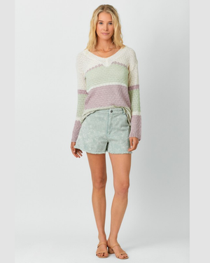 Woman wearing a striped sweater and shorts on a plain background