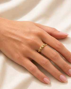 Gold ring on a person's finger against a beige fabric background