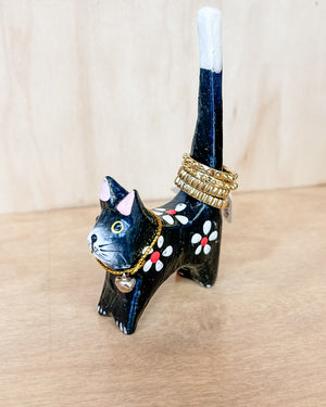 Cat-shaped jewelry holder with rings on a wooden surface