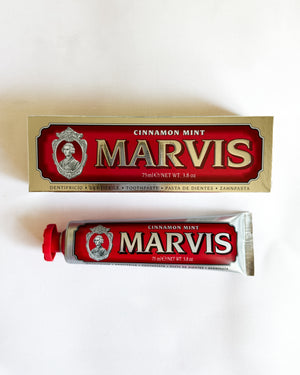 A tube and box of Marvis Cinnamon Mint toothpaste arranged on a plain white background.