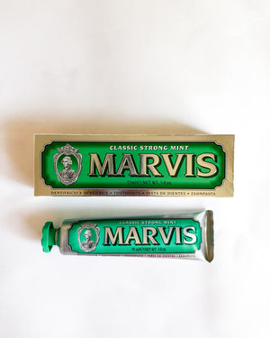 A tube and box of Marvis Classic Strong Mint toothpaste arranged on a plain white background.