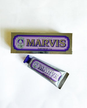 A tube of Marvis toothpaste and its corresponding box packaging, both featuring the brand's signature purple and gold design, displayed on a clean white background.