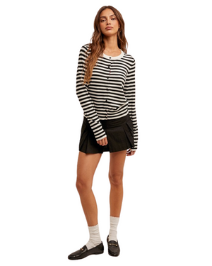Woman wearing a black and white striped long-sleeve shirt and black skirt on a white background