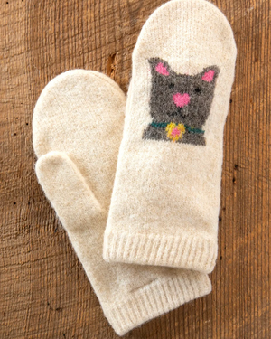Pair of cream-colored mittens with a cat design on a wooden surface