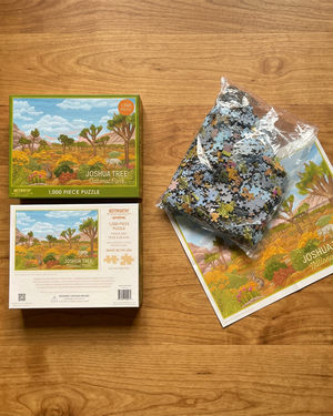 A 1000-piece jigsaw puzzle about Joshua Tree National Park, shown with its illustrated box on the left and the puzzle pieces in a clear plastic bag on the right, all on a plain white background.