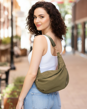 Woman holding a green crossbody bag on a city street