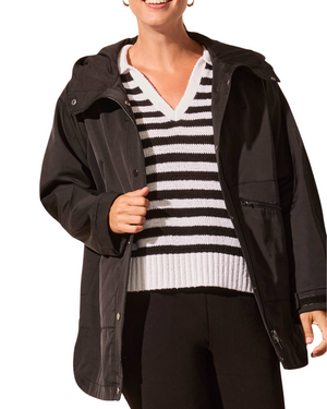 Person wearing a black jacket over a striped sweater on a white background