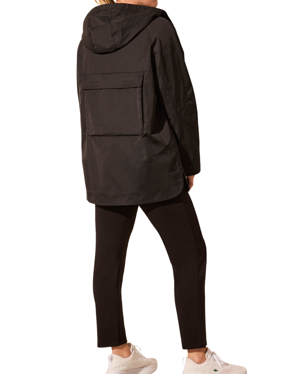 Person wearing a black hooded jacket and pants on a white background