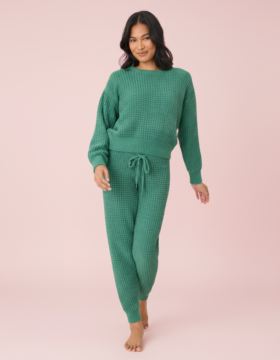 Woman wearing a green waffle knit pajama set on a white background