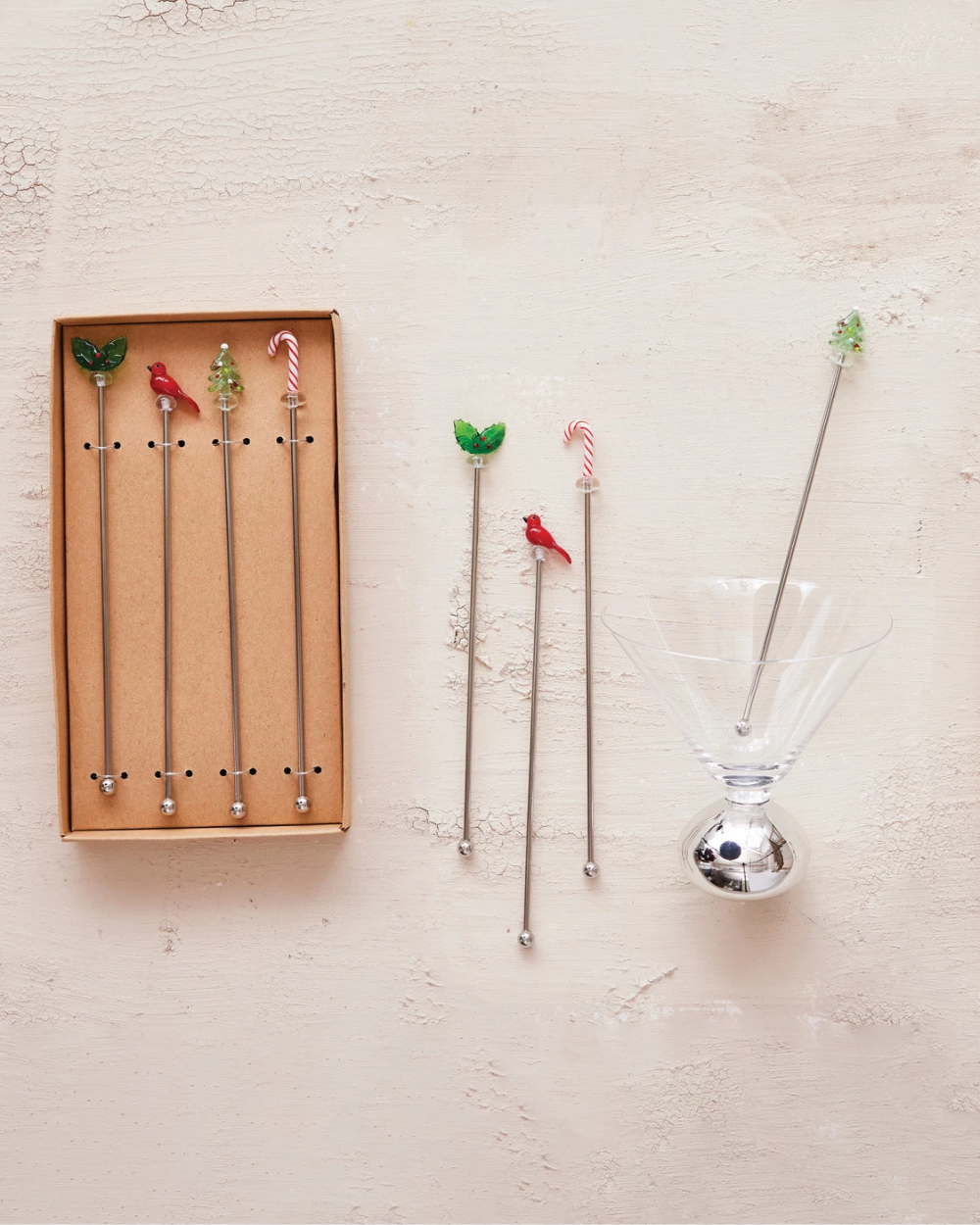 Set of decorative cocktail stirrers with a box on a light background