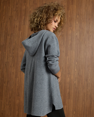 Woman wearing a gray hooded coat against a wooden background