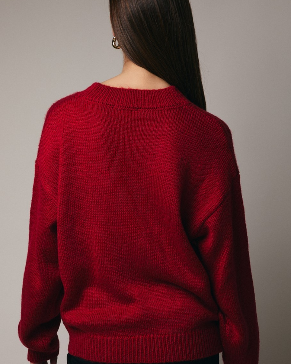 Red sweater worn by a person on a plain background