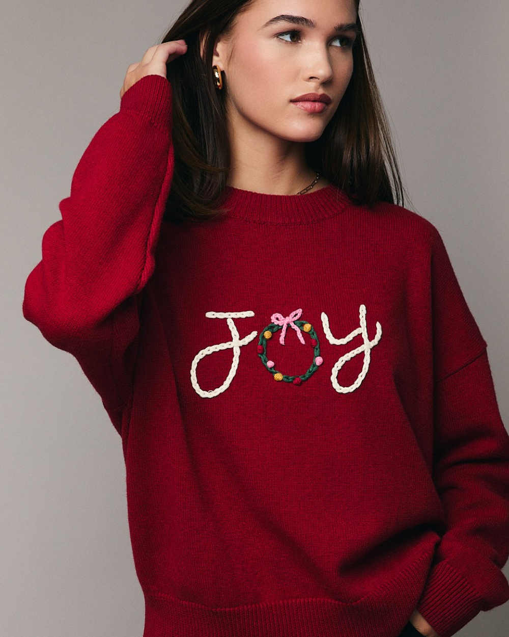 Red sweater with 'JOY' and a wreath design on a plain background