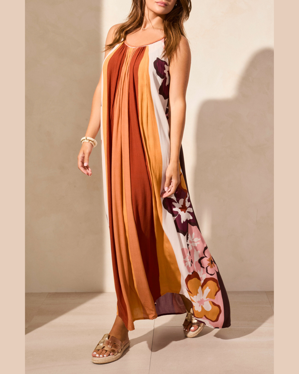 Woman wearing a long, patterned dress with a neutral background