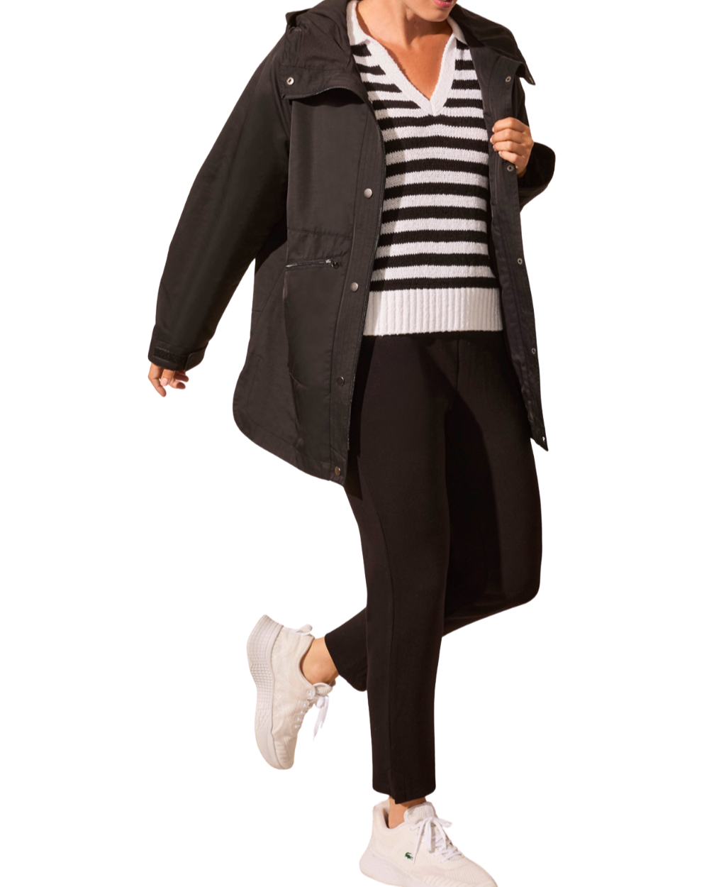 Person wearing a black coat, striped sweater, and black pants on a white background