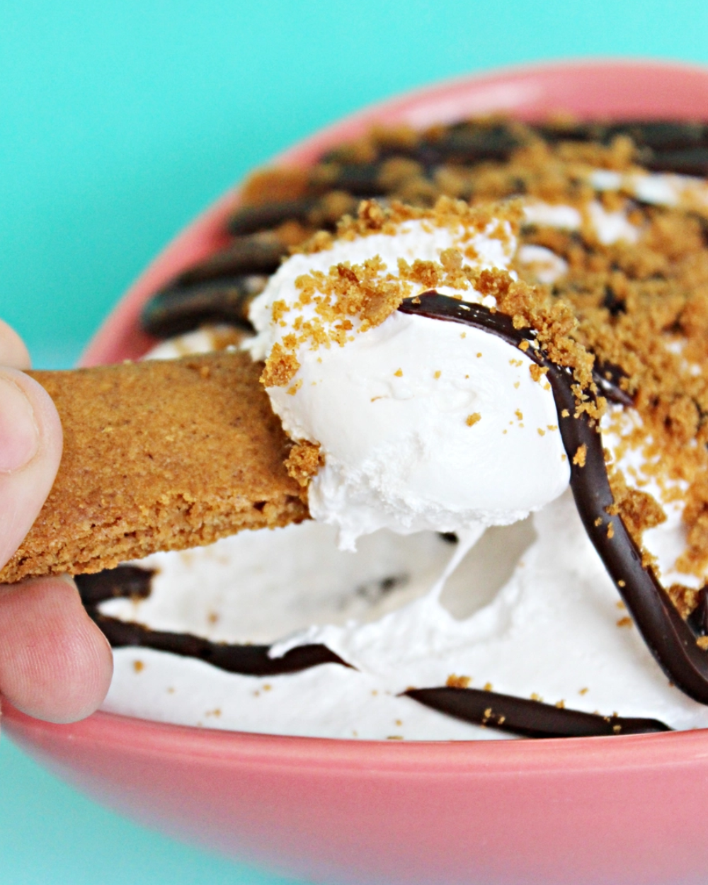 Stack of s'mores with a colorful container on a pink background