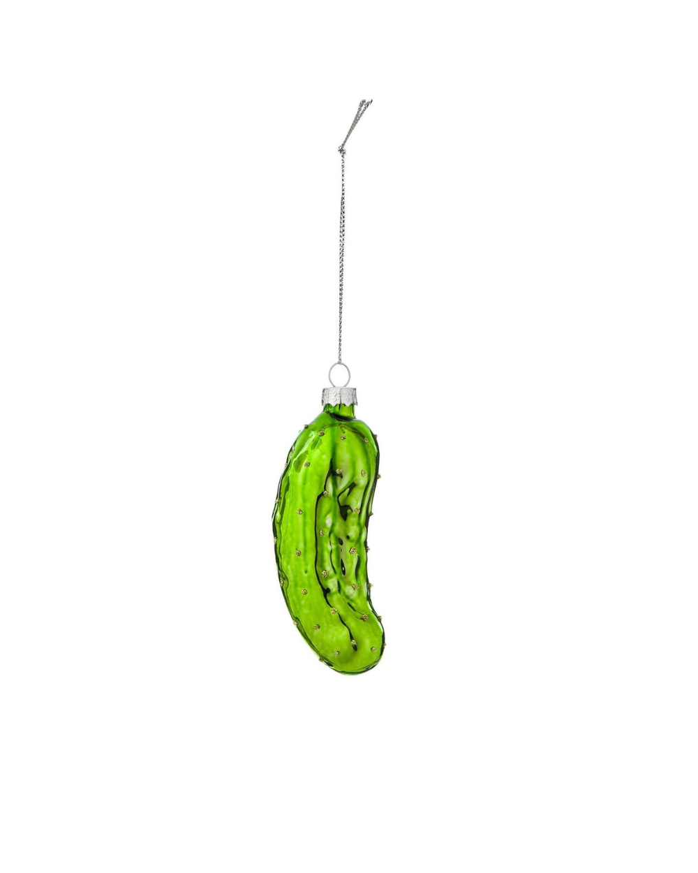 Green pickle ornament being held by a hand against a Christmas tree background