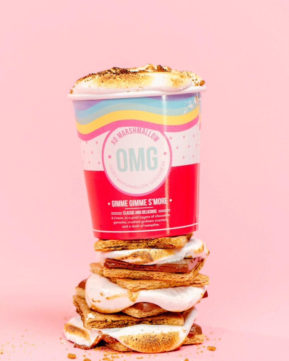 Stack of s'mores with a colorful container on a pink background