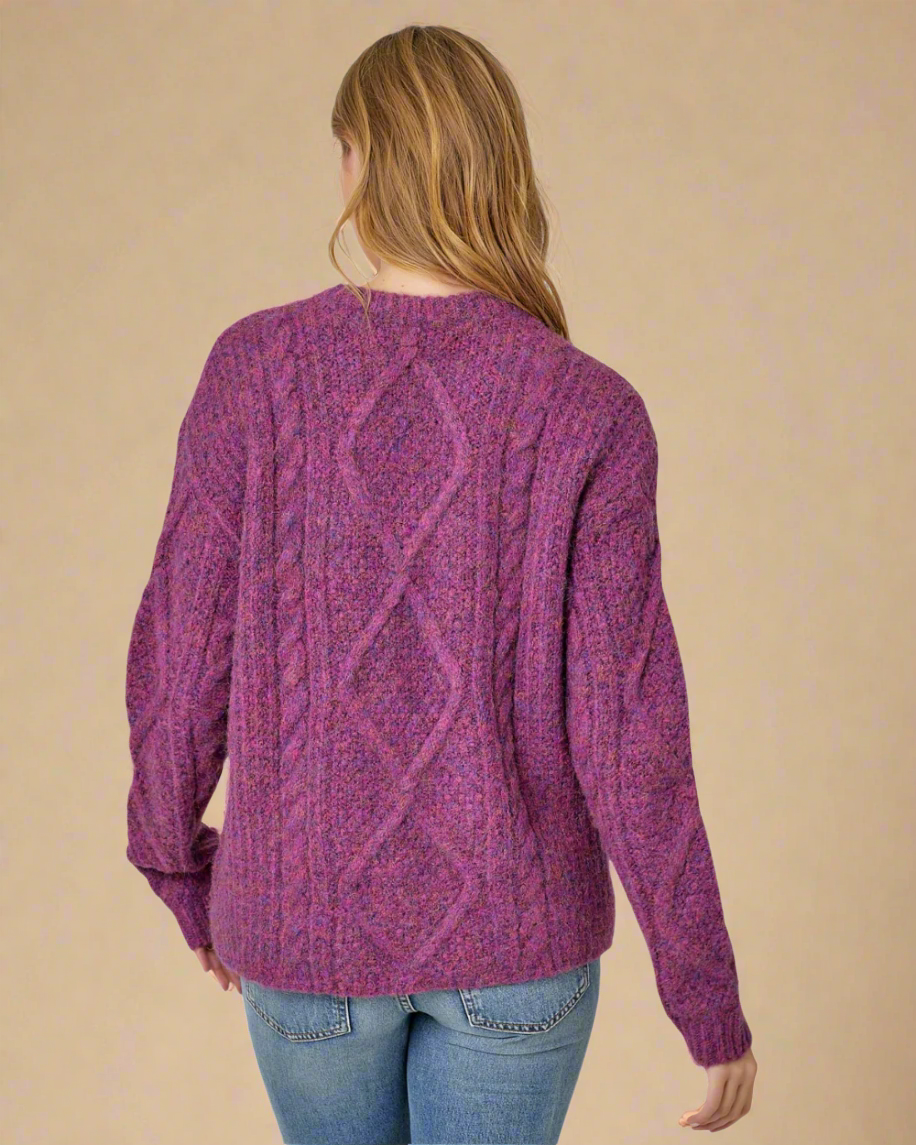 Person wearing a purple cable knit sweater on a white background