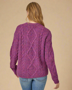 Person wearing a purple cable knit sweater on a white background