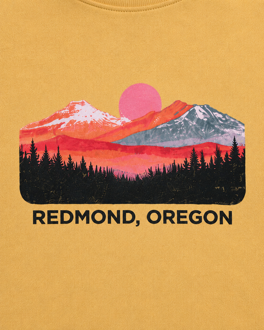 A mustard yellow crewneck sweatshirt featuring a colorful mountain sunset graphic with the text 'REDMOND, OREGON' printed below it, displayed on a clean white background.