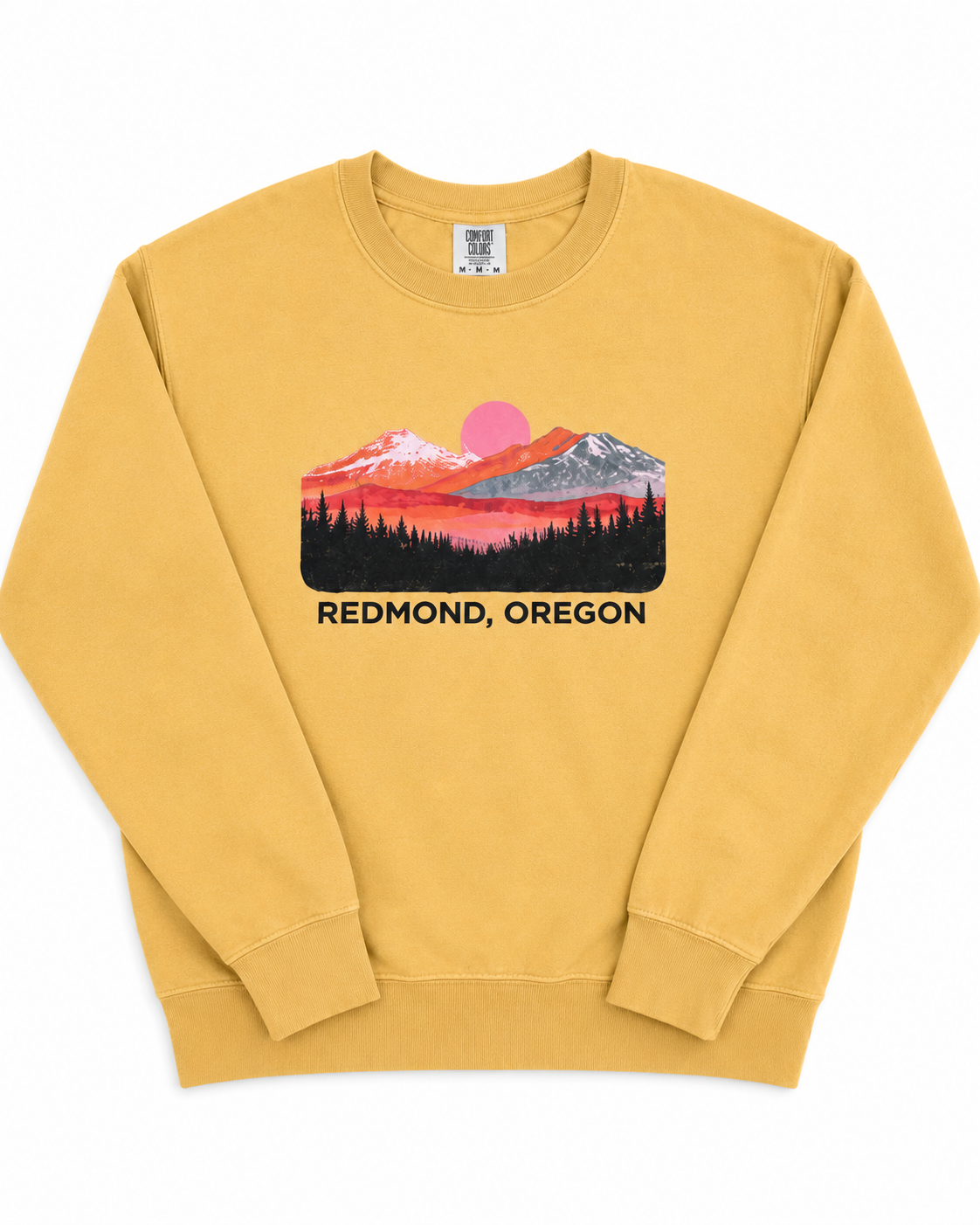 A mustard yellow crewneck sweatshirt featuring a colorful mountain sunset graphic with the text 'REDMOND, OREGON' printed below it, displayed on a clean white background.