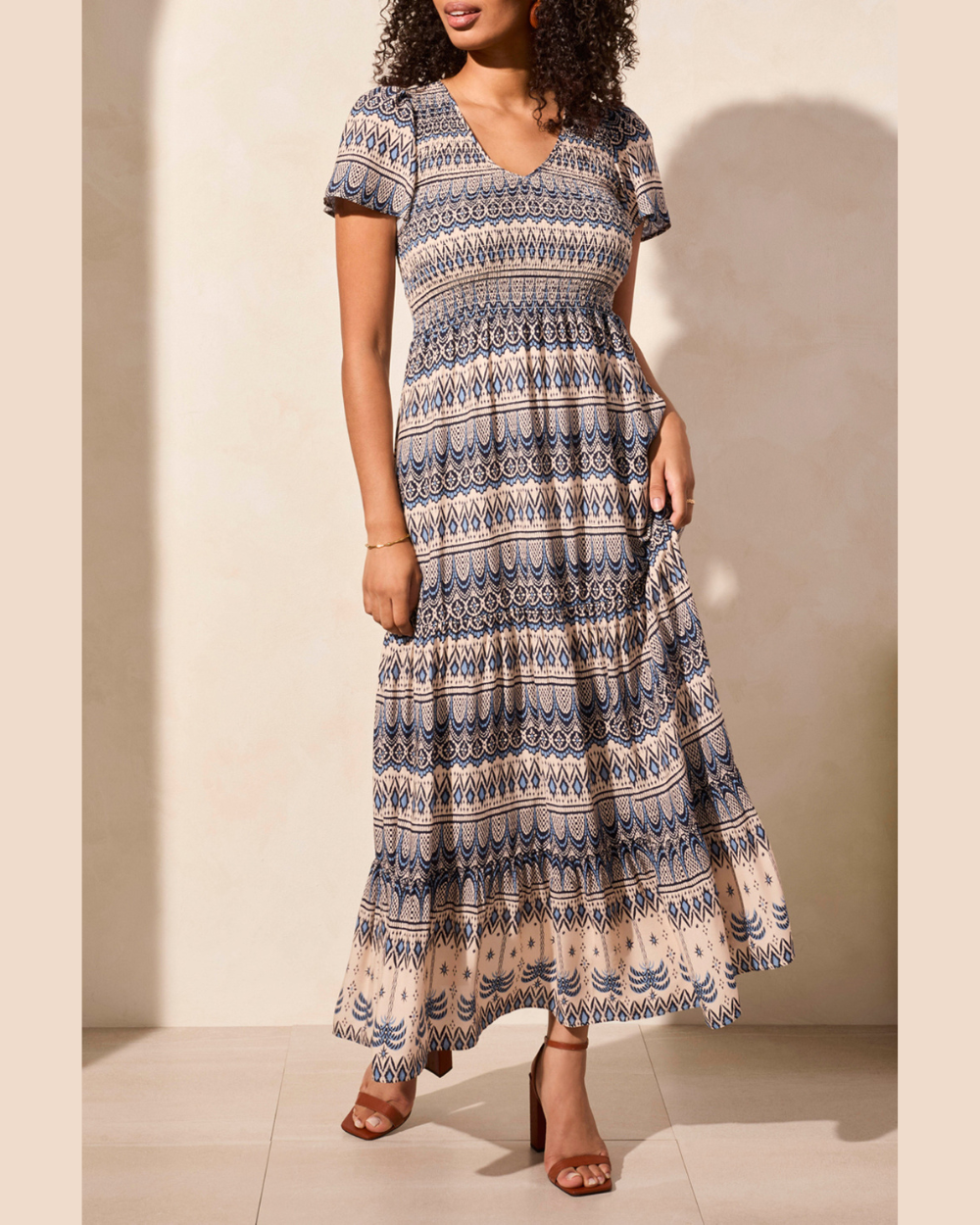 Woman wearing a patterned dress against a neutral background