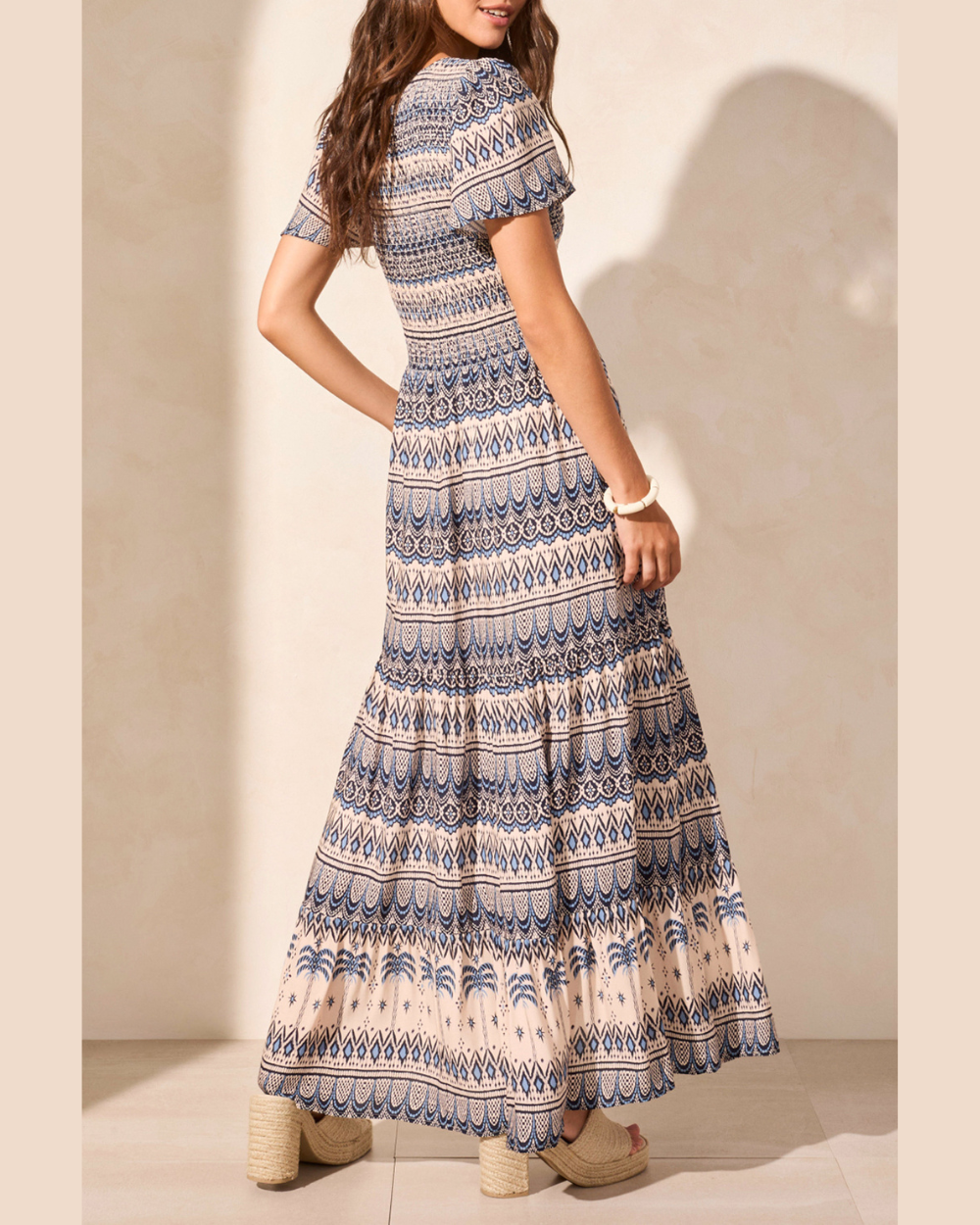 Woman wearing a patterned dress against a neutral background