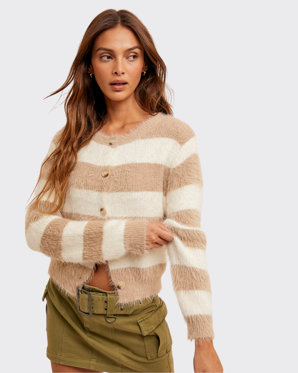 Woman wearing a beige and white striped sweater with a plain background