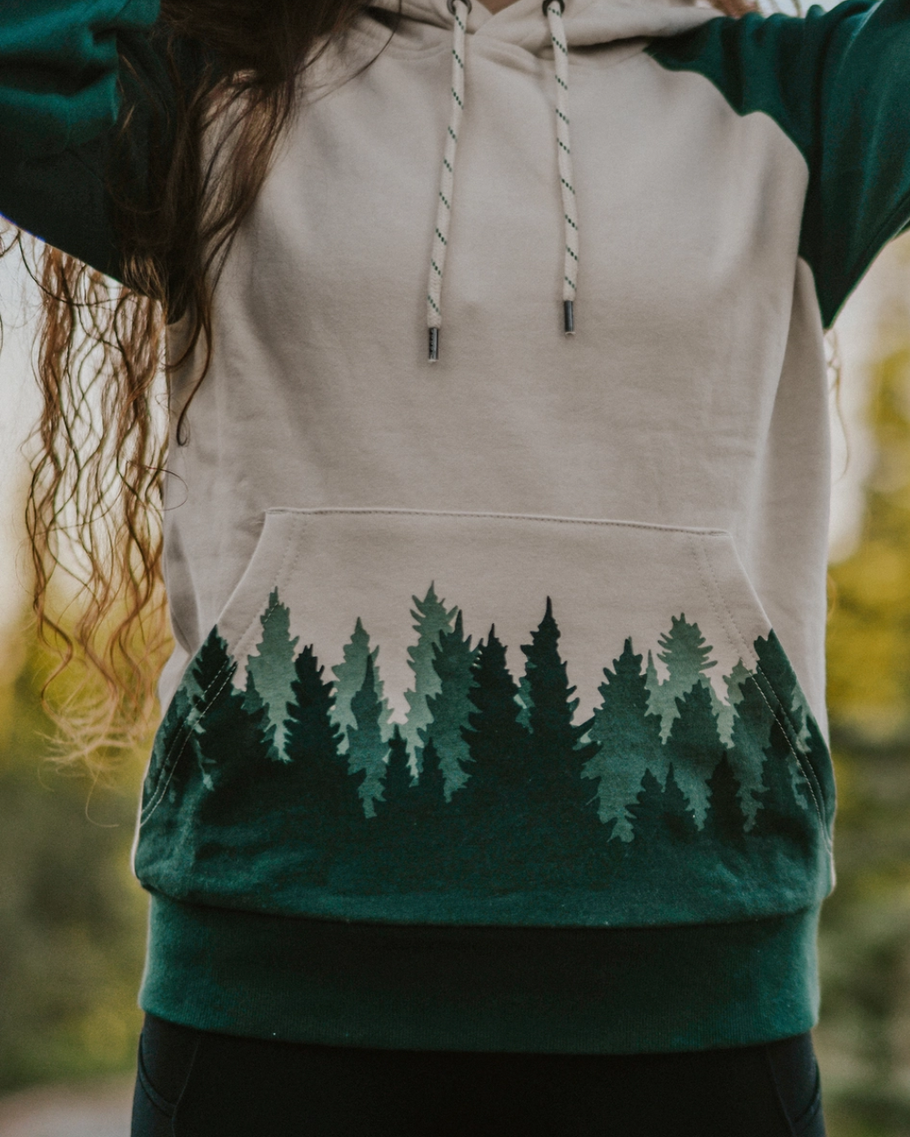 Person wearing a hoodie with a forest design outdoors