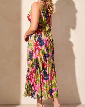 Woman wearing a colorful floral dress against a beige wall.